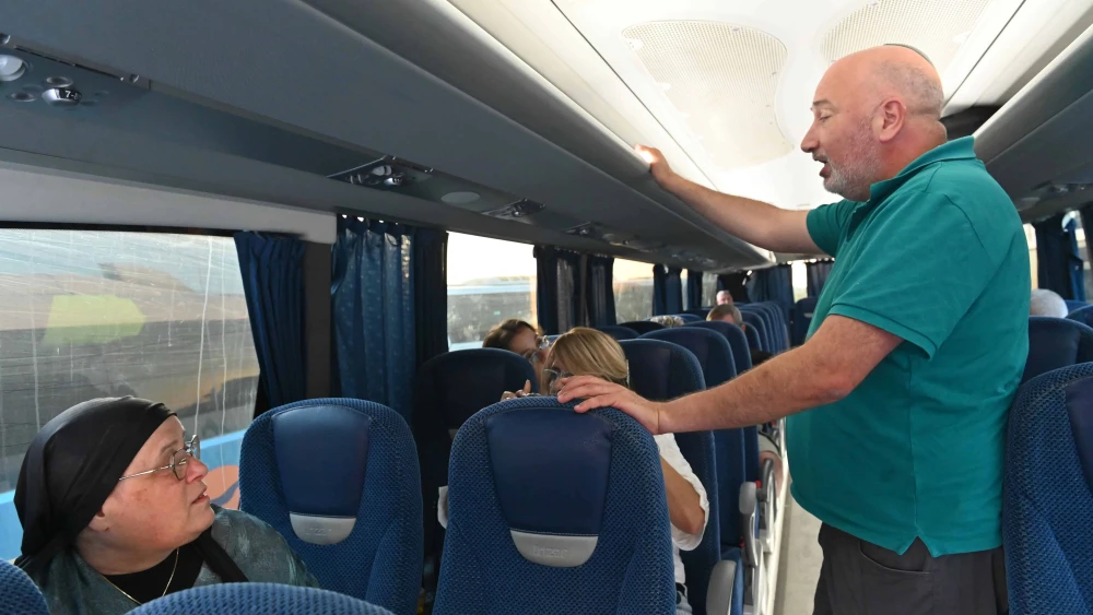 Ayelet Keene speaks with a passenger on a bus en route to a rally in support of the current Israeli government, outside the Supreme Court in Jerusalem, on June 5, 2025. Photo by Canaan Lidor.
