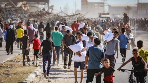 Palestinians carrying bags of flour outside a distribution site run by the Gaza Humanitarian Foundation in Deir al-Balah, the central Gaza Strip, on May 28, 2025. Photo by Ali Hassan/Flash90.