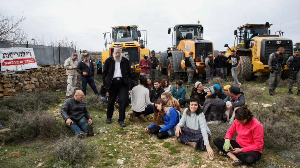 Civil administration representatives and Israelii Border Police arrive with tractors to begin preparations for evacuation and demolition of the illegal Jewish neighborhood of Netiv Ha’avot, as Jewish settlers block their way, Feb. 6, 2018. Photo by Gershon Elinson/Flash90.