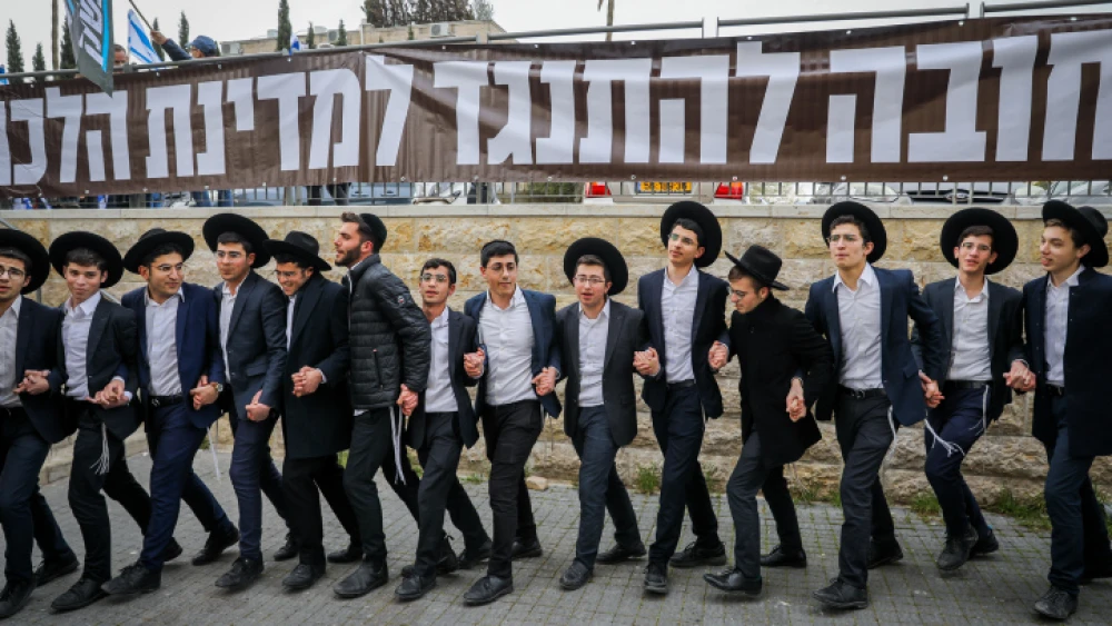 Haredi Jewish men dance as part of a counter-demonstration during a protest against the planned judicial overhaul outside the home of head of the Shas party Aryeh Deri in Jerusalem, March 23, 2023. Photo by Flash90