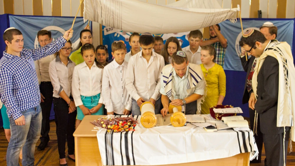 Participants in the Bar/Bat Mitzvah Family Camp reading from a Torah scroll in the Siberian city of Novosibirsk in August 2014. Credit: Roman Ibragimov.