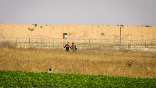 Palestinians wave a flag near the border fence east of Kahn Yunis in the southern Gaza Strip, on May 19, 2017. Credit: Abed Rahim Khatib/ Flash90.