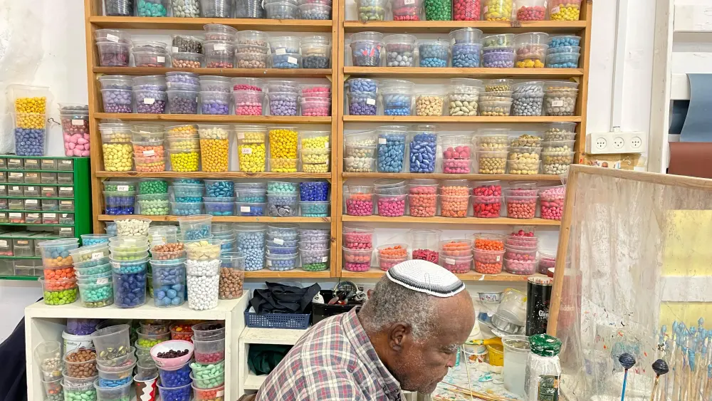 Atalai, 77, paints beads at Yad LaKashish’s Paper Mache Workshop. Photo by Judith Segaloff.