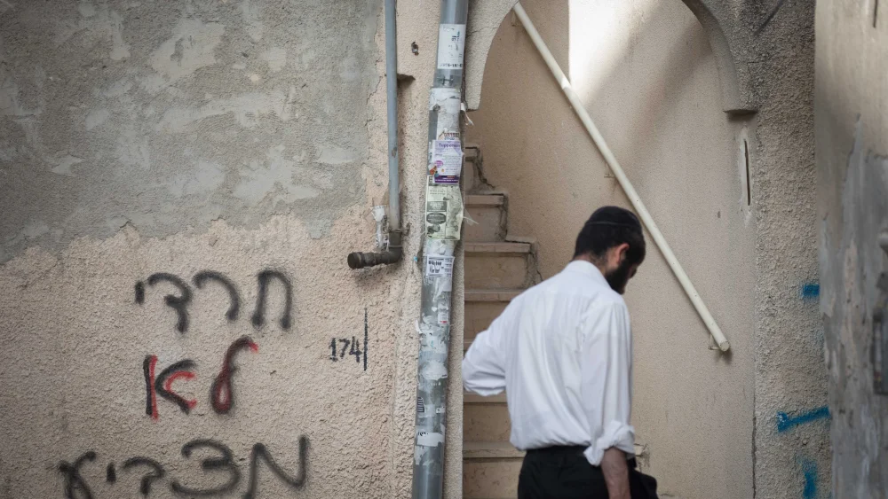 An Ultra-Orthodox Jewish man walks close to a graffiti saying "ultra-orthodox don't vote", n the ultra orthodox jewish neighborhood of Mea Shearim, Jerusalem, june 3, 2019. Photo By Noam Revkin Fenton / FLASH90