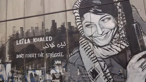 The Israeli security fence in Bethlehem is pictured here painted with graffiti depicting Popular Front for the Liberation of Palestine terrorist Leila Khaled. Rabab Abdulhadi, a professor at San Francisco State University, met with Khaled on a trip funded by the state of California. Credit: Bluewind via Wikimedia Commons.