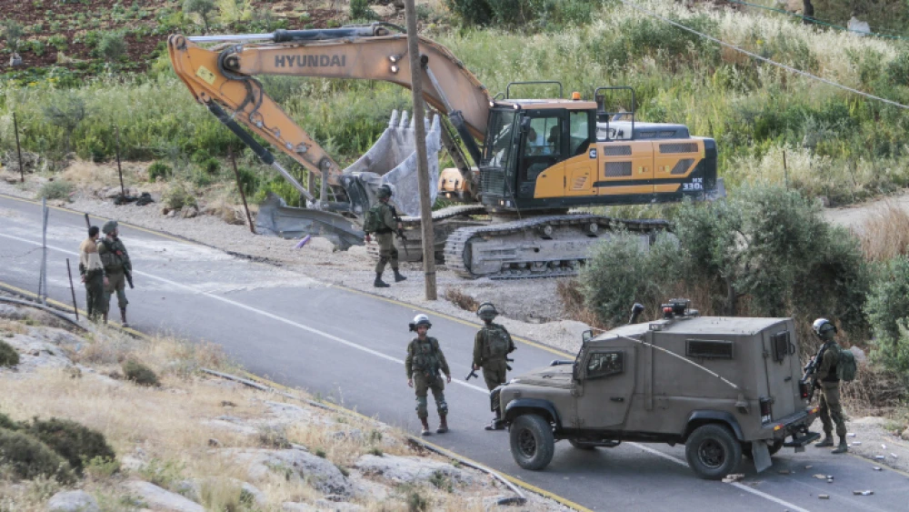 IDF soldiers stand guard as a bulldozer demolishes a Palestinian house that was built without a permit in the village of Beit Dajan, east of Nablus, May 9, 2022. Photo by Nasser Ishtayeh/Flash90.