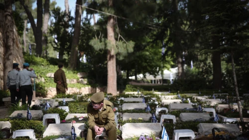 An Israeli soldier sits next to grave of fallen soldier at the Mount Herzl military cemetery in Jerusalem during Israeli Memorial Day, which commemorates the deaths of Israeli soldiers killed in wars since 1860, as well as Israeli victims of terror. April 18, 2018. Photo by Miriam Alster/Flash90