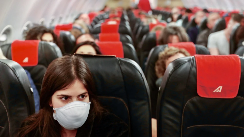 A woman wears a face mask for fear of the SARS-Cov-2 virus on a flight from Tel Aviv to Rome on Feb. 21, 2020. Photo by Nati Shohat/Flash90.