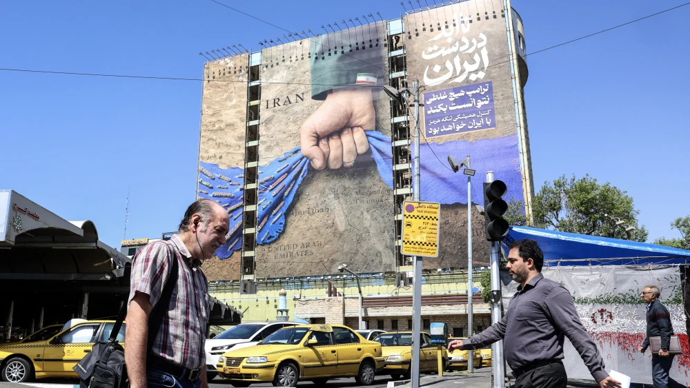 Iranians walk past a large billboard referring to the Strait of Hormuz in Tehran's Vanak Square on April 15, 2026. Photo by AFP via Getty Images.