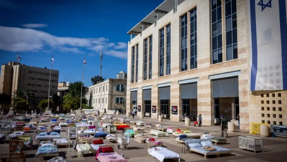 People walk between hundreds of beds, each symbolizing a captive held by Hamas in the Gaza Strip, outside Jerusalem City Hall, Oct. 30, 2023. Photo by Yonatan Sindel/Flash90.