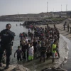 Members of the Spanish Guardia Civil USECIC stand watch over migrants on Tarajal beach after tens of thousands crossed the border between Spain and Morocco in Ceuta, Spain, on July 31, 2026. Photo by Adri Salido/Getty Images.