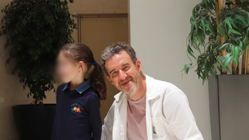 A 7-year-old girl who was critically injured in an Iranian missile attack during "Operation Roaring Lion" poses with a surgeon at Schneider Children’s Medical Center after being discharged, April 2026. Credit: Courtesy of Schneider Children’s Medical Center.