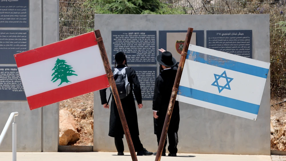 Ultra-Orthodox Jewish men stand beside Israeli and Lebanese flags at a memorial site on the border with Lebanon in northern Israel, on July 1, 2026. Photo by Jack Guez / AFP via Getty Images.