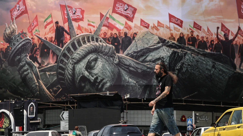 An Iranian man walks past an anti-U.S. billboard at Enghelab Square in central Tehran on Aug. 3, 2026, as Iran denies holding new negotiations with the United States to end the six-month war sparked by surprise U.S. and Israeli strikes on Feb. 28. Photo by Atta Kenare/AFP via Getty Images.