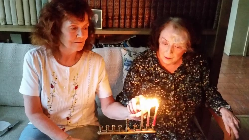 Margery B. Sterns (right), 96, a a longtime resident of San Francisco, lights the menorah with her daughter Sandra. Margery recalls her Russian immigrant parents lighting the menorah as one of her top memories of Hanukkah. Credit: Courtesy.