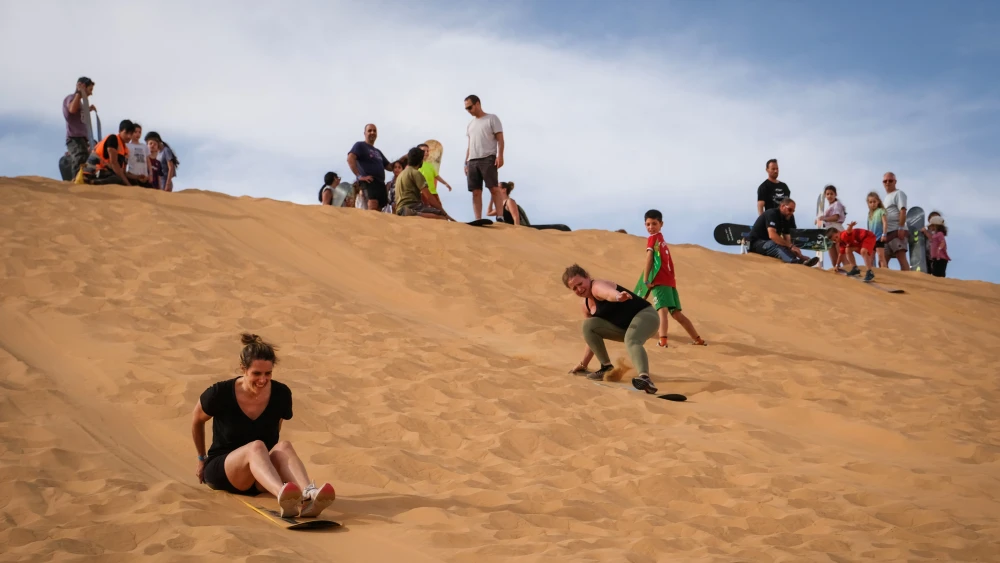 People surf on a sand dune in the Western Negev Desert in southern Israel, April 22, 2022. Photo by Noam Revkin Fenton/Flash90.