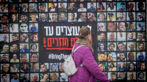 People walk next to pictures of civilians held hostage by Hamas terrorists in Gaza, in Jerusalem, Feb. 12, 2024. Photo by Chaim Goldberg/Flash90.
