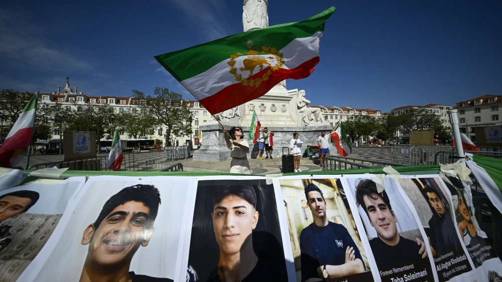 Participants gather to hold the Lion and Sun flag aloft for 40,000 seconds, symbolizing “the memory of the thousands of Iranians killed by the Islamic Republic’s repression” and in tribute to the victims of the events of past January 18 and 19 during a rally and vigil in Rossio Square organized by the Iranian Voices movement in Portugal, as part of an international mobilization taking place in over 100 cities worldwide, with the aim of “affirming the Iranian people’s connection to their historic Lion and Sun flag, a symbol deeply rooted in Iran’s identity and heritage” on June 13, 2026 in Lisbon, Portugal. Photo by Horacio Villalobos#Corbis/Getty Images.
