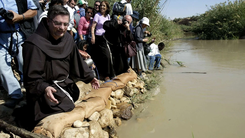 Jose Rodriguez Carballo, the Spanish worldwide head of the Catholic Franciscan order, kneels at the Jordan River at Qasr al-Yehud  on Oct. 30, 2003. The river bank, where Jesus is believed to have been baptized, is in an Israeli army military zone along the Jordanian border and was opened specially to allow hundreds of Catholic worshippers to make a pilgrimage to the site. Photo by David Silverman/Getty Images.
