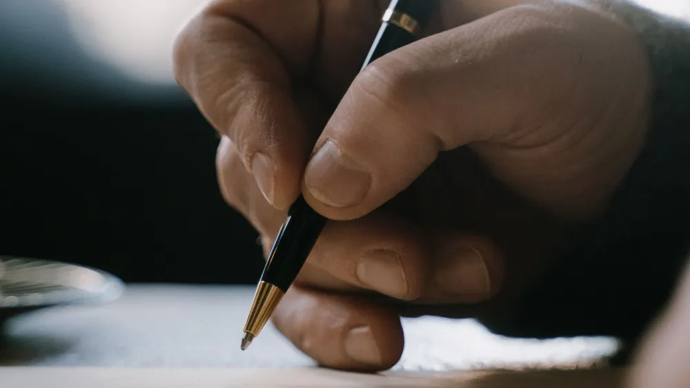 A person writing with a pen. Credit: Cottonbro Studio/Pexels.