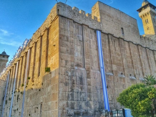 Israel flags decorate the 2,000-year-old Cave of the Patriarchs complex in Hebron in anticipation of Independence Day, May 2018. The same Herodian masonry is used for the Western Wall in Jerusalem. Photo by Yishai Fleisher.