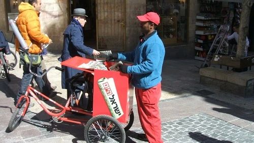 Click photo to download. Caption: Distribution of free copies of the Israel Hayom newspaper in Jerusalem. Credit: Wikimedia Commons.