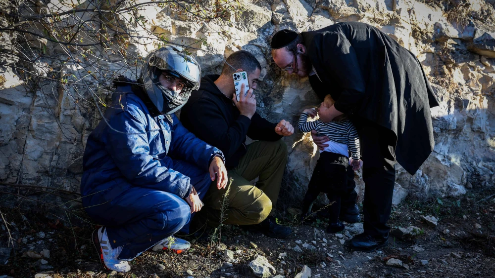 People take cover as siren warns of incoming missiles from Lebanon in the northern Israeli city of Tzfat, November 13, 2024. Photo by David Cohen/Flash90 *** Local Caption *** צפת מלחמה פגיעה טילים רצים אזעקה