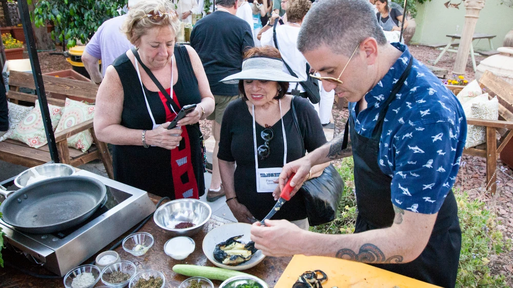 Chef Michael Solomonov prepares a dish in front of two ladies. Credit: Jamie Gordon.