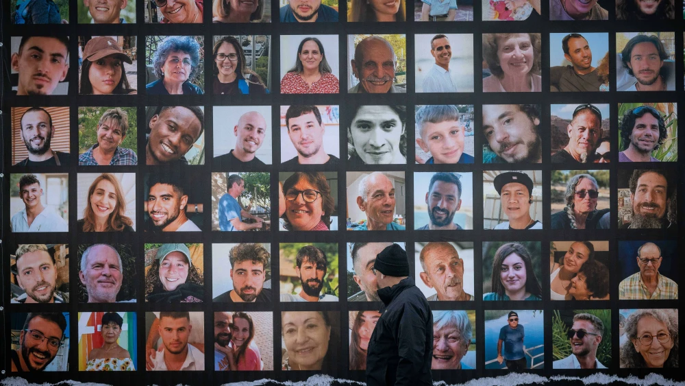 People walk next to pictures of civilians held hostage by Hamas terrorists in Gaza, in Jerusalem, November 22, 2023. Photo by Yonatan Sindel/Flash90 *** Local Caption *** דגל ישראל תמונות נעדרים לוח מודעות מלחמה