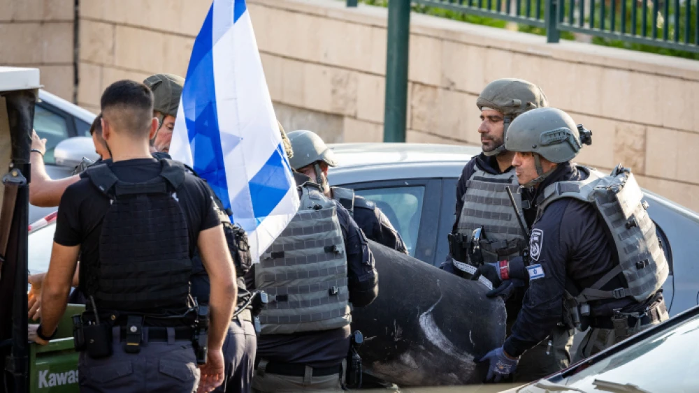 Police dispose of a rocket fragment that damaged a parking lot in Netivot in southern Israel, on May 13, 2023. Photo by Yonatan Sindel/Flash90.