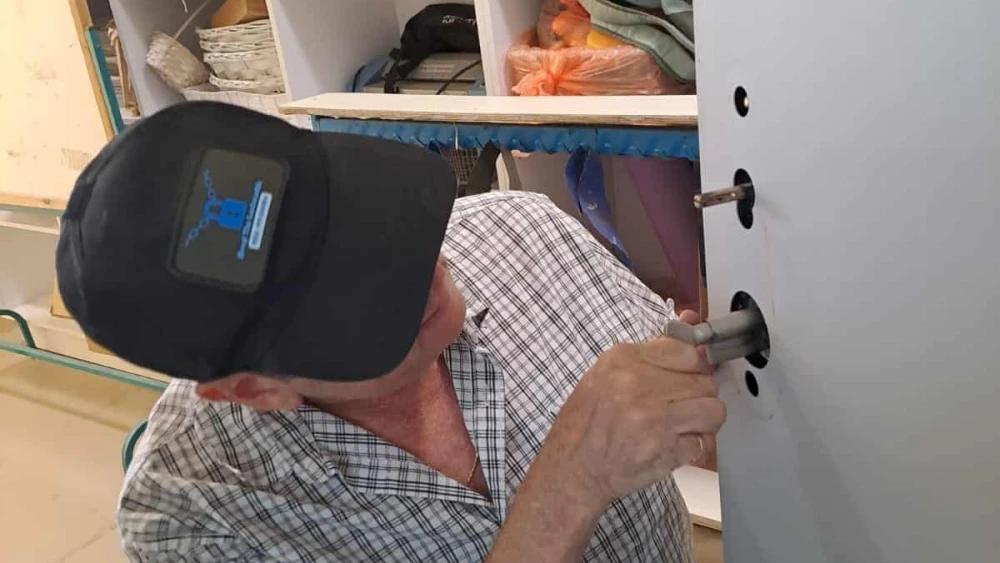 A locksmith makes repairs at Kibbutz Nir Am, Aug. 20, 2024. Photo by Vanessa Fisher.