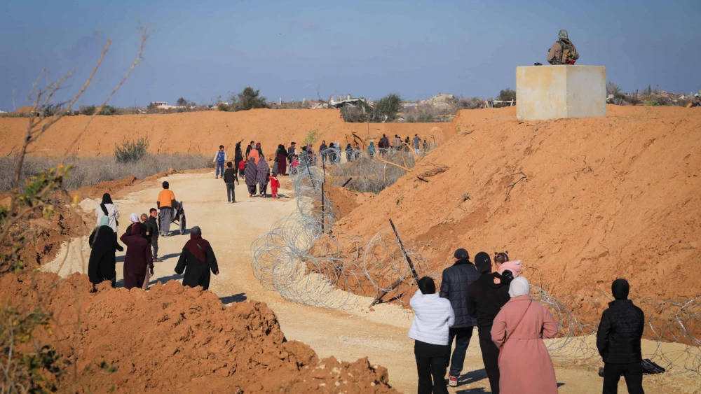 Gazans walk alongside an Israeli army post in northern Gaza, Jan. 28, 2025. Photo by Ali Hassan/Flash90.
