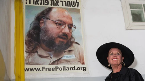 Esther Pollard walks past a poster of her husband, Jonathan Pollard, before speaking to reporters outside of her Jerusalem home on July 29, the day after it was announced that Jonathan, jailed for nearly 30 years over giving Israel classified information on America, will be released in November 2015. Photo by Flash90.