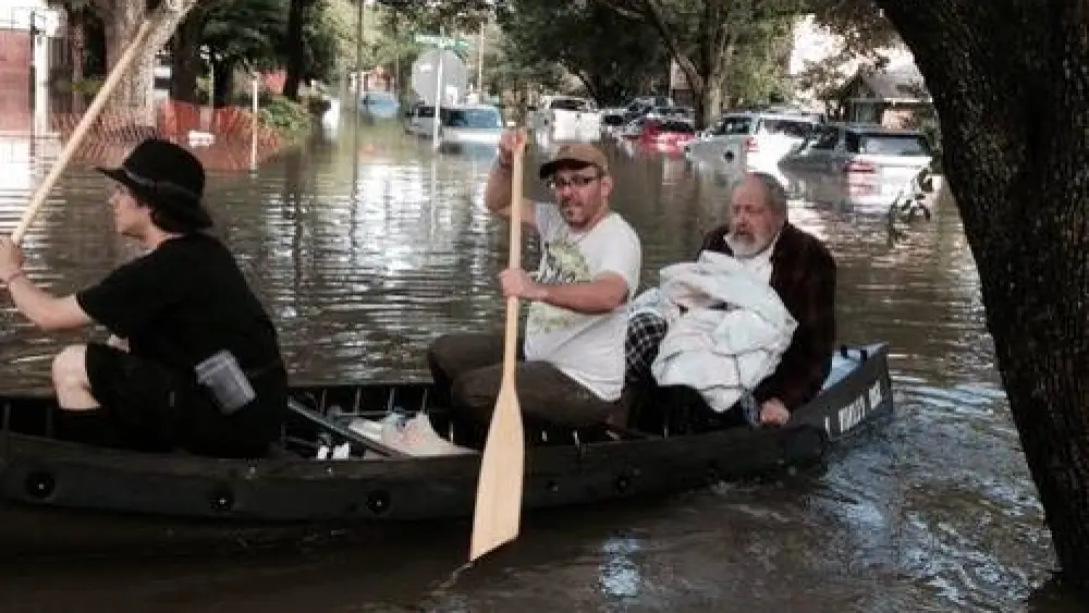 The iconic photo of Morgan Davies (far left) and Donniel Ogorek (center) rescuing Rabbi Joseph Radinsky (right) from the flood in Houston. Credit: Robert Levy via Facebook.