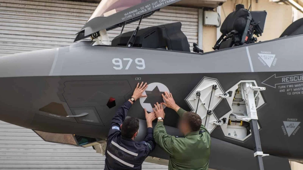 Ground crew members apply an Israeli Air Force insignia to the fuselage of an F-35I “Adir” fighter jet, one of three newly arrived U.S.-made aircraft at Nevatim Airbase in the Negev, on Jan. 18, 2026. Credit: IDF.