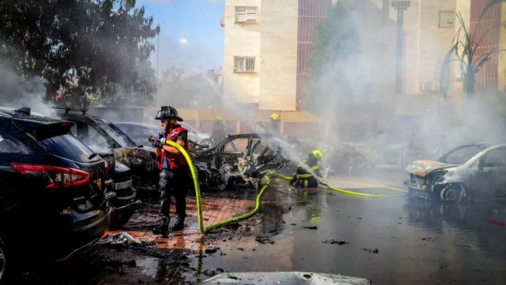 Firefighters tackle burning cars set aflame by a rocket launched from the Gaza Strip that landed in the southern Israeli city of Beersheva on Oct. 7, 2023. Photo by Dudu Greenspan/Flash90.
