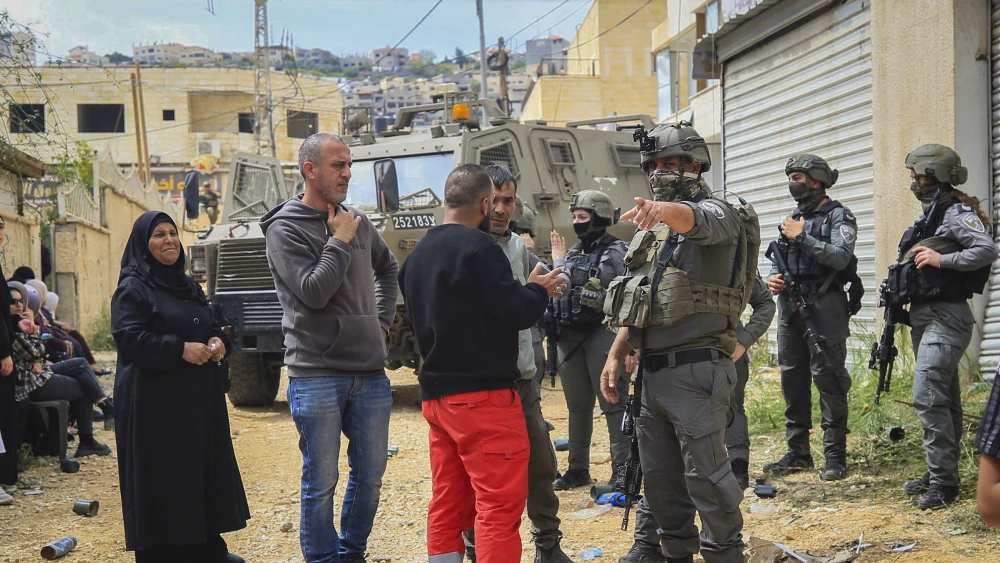 Israeli security forces stand guard as Palestinians wait at a checkpoint