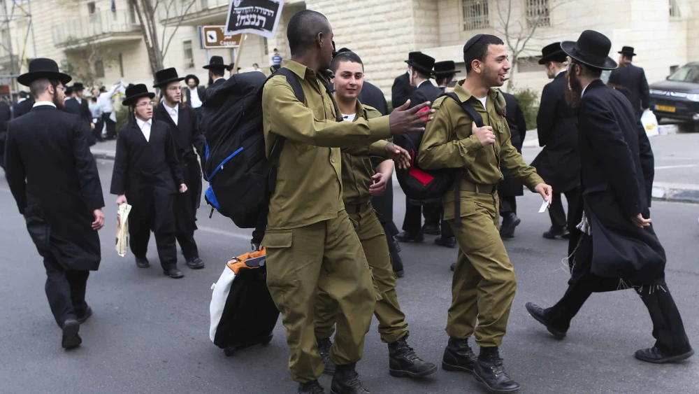 Israeli soldiers walk by a protest in Jerusalem attended by hundreds of thousands of ultra-Orthodox Jews against a proposal to introduce compulsory military service to the haredi community, March 02, 2014. Photo by Nati Shohat/Flash90.