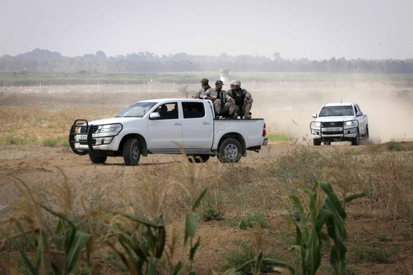 Palestinian terrorists of the Ezzedine al-Qassam Brigades, Hamas' armed wing, sit in the back of a pick-up truck watching Israeli bulldozers working along a barbed wire fence that separates Khan Yunis in the southern Gaza Strip and the Israeli border, on June 10, 2015. Photo by Abed Rahim Khatib/Flash 90.