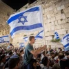 Israelis wave flags at the Western Wall in Jerusalem's Old City on the eve of Jerusalem Day, May 9, 2021. Photo by Yonatan Sindel/Flash90.