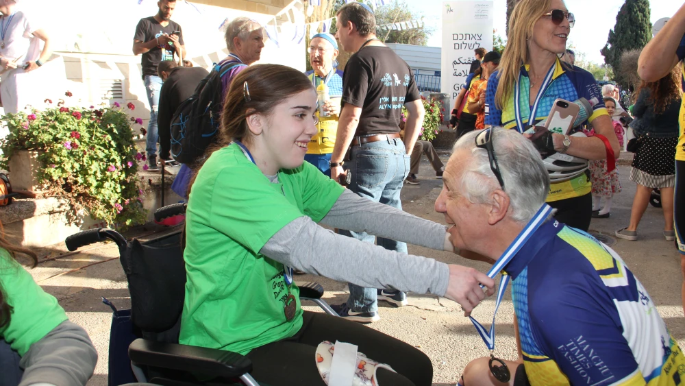 A cyclist received a medal from a young hospital patient. Credit: ALYN.