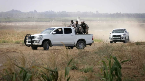 Palestinian terrorists of the Ezzedine al-Qassam Brigades, Hamas' armed wing, sit in the back of a pick-up truck watching Israeli bulldozers working along a barbed wire fence that separates Khan Yunis in the southern Gaza Strip and the Israeli border, on June 10, 2015. Photo by Abed Rahim Khatib/Flash 90.