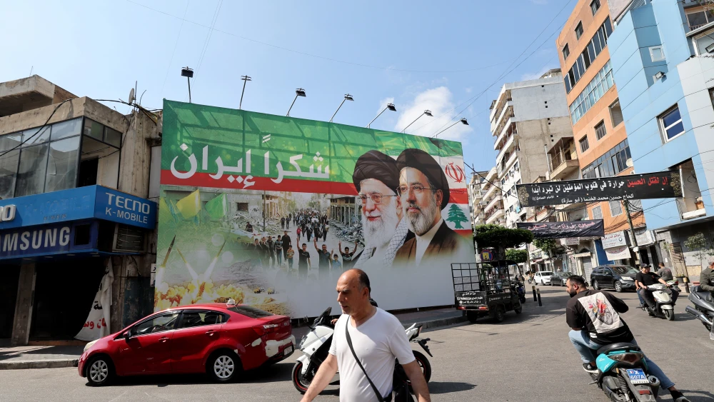 A man walks past a billboard depicting slain Iranian Supreme Leader Ayatollah Ali Khamenei and his son, Supreme Leader Ayatollah Mojtaba Khamenei, with Arabic writing that reads: "Thank you Iran," in Beirut, June 15, 2026. Photo by Anwar Amro/AFP via Getty Images.