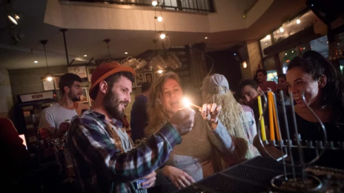 Young Israelis light candles for the Jewish holiday of Hanukkah at a bar in Tel Aviv on Dec. 8, 2015. Photo by Miriam Alster/Flash90.