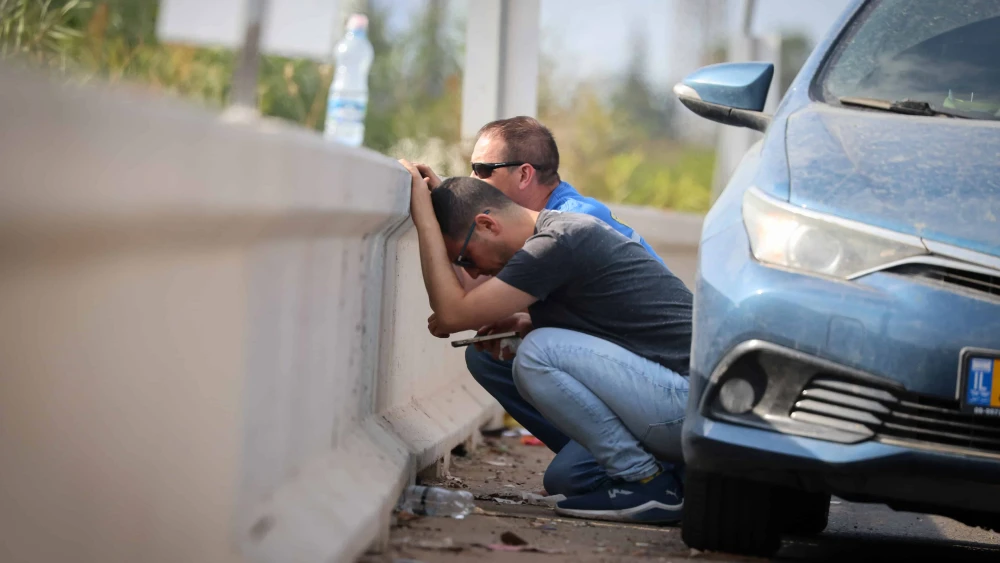 People take cover on a road near Tel Aviv as air-raid sirens warn of incoming rocket fire from the Gaza Strip, Oct. 10, 2023. Photo by Yossi Zamir/Flash90.