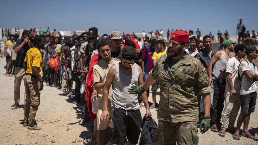 Migrants wait to receive water on the beach next to the CETI (Centros de Estancia Temporal de Inmigrantes) in Ceuta, Spain, on Aug. 2, 2026. Spain's interior ministry deployed members of the armed forces and Guardia Civil officers there after tens of thousands of migrants suddenly entered the Spanish enclave in North Africa.