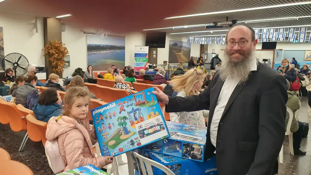 Rabbi Menachem Traxler gives a building set to a child. Credit: Pantry Packers.