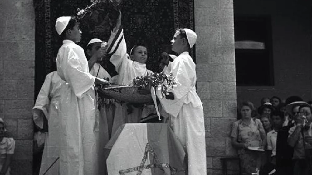 Kindergarten children symbolically give KKL-JNF bikkurim (“first fruits”) during Shavuot celebrations in the courtyard of the National Institutions in Jerusalem (the historic complex on King George Street housing the central Zionist organizations), May 1947. Credit: Efraim Ilani, KKL-JNF Photo Archive.