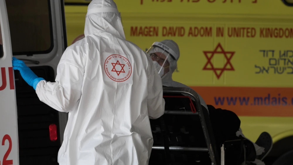 Magen David Adom workers wearing protective clothing as a preventive measure against the coronavirus evacuate a patient outside the new coronavirus unit at Shaare Zedek Medical Center in Jerusalem on April 6, 2020. Photo by Nati Shohat/Flash90.