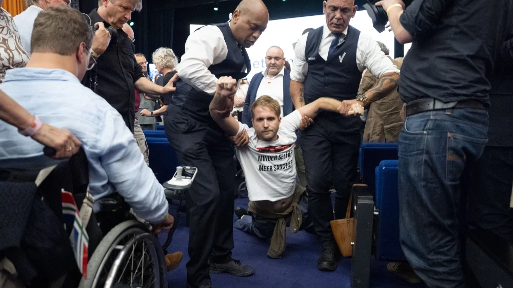 Le 27 septembre 2026, au centre de congrès RAI d'Amsterdam, des agents de sécurité évacuent un manifestant portant un t-shirt sur lequel on peut lire « Moins de selfies, plus de sanctions ». Photo de Jeroen Jumelet/ANP/AFP via Getty Images.